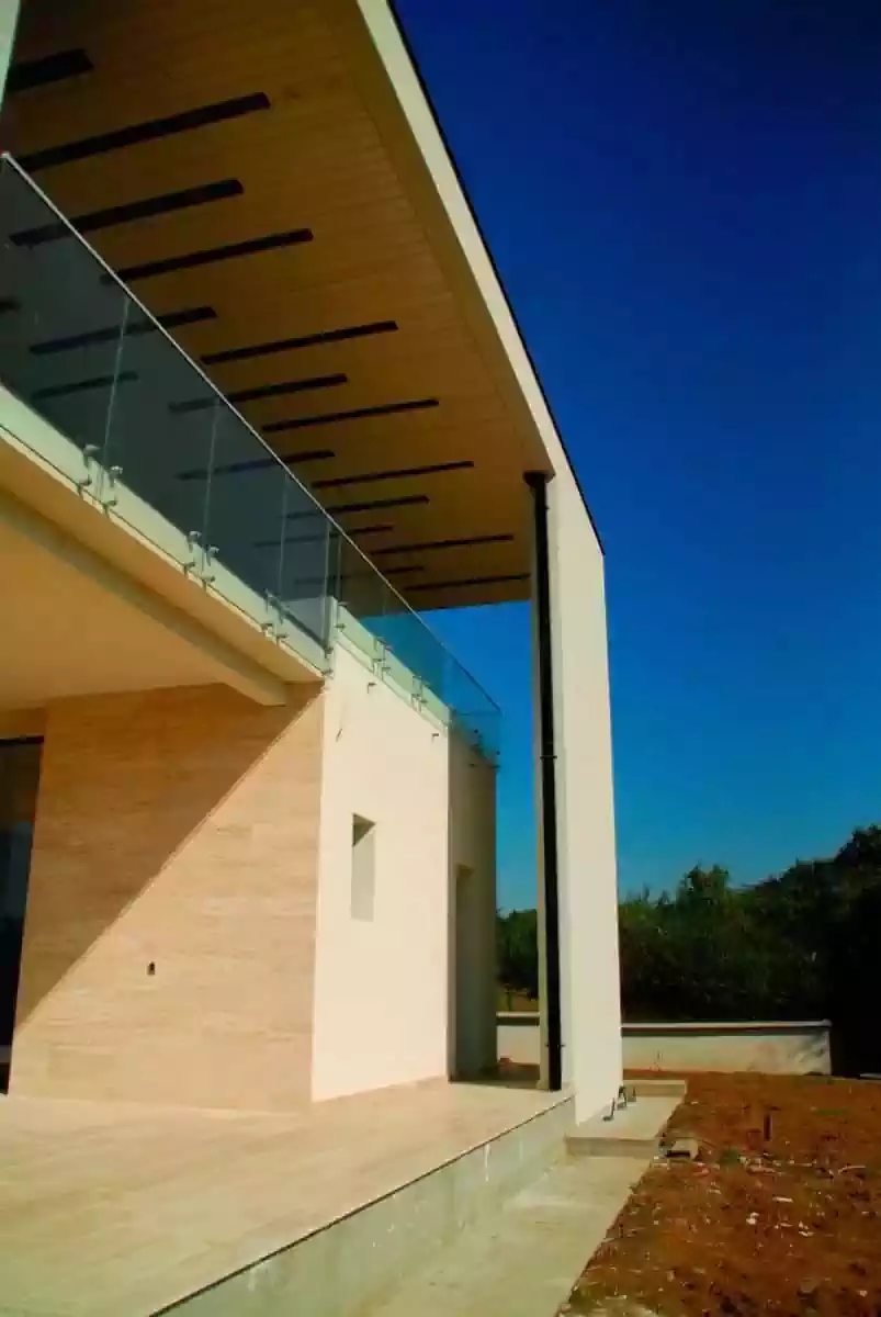 Modern house detail of floating roof above balcony clad in glass and stone. Design by architectural firm harare