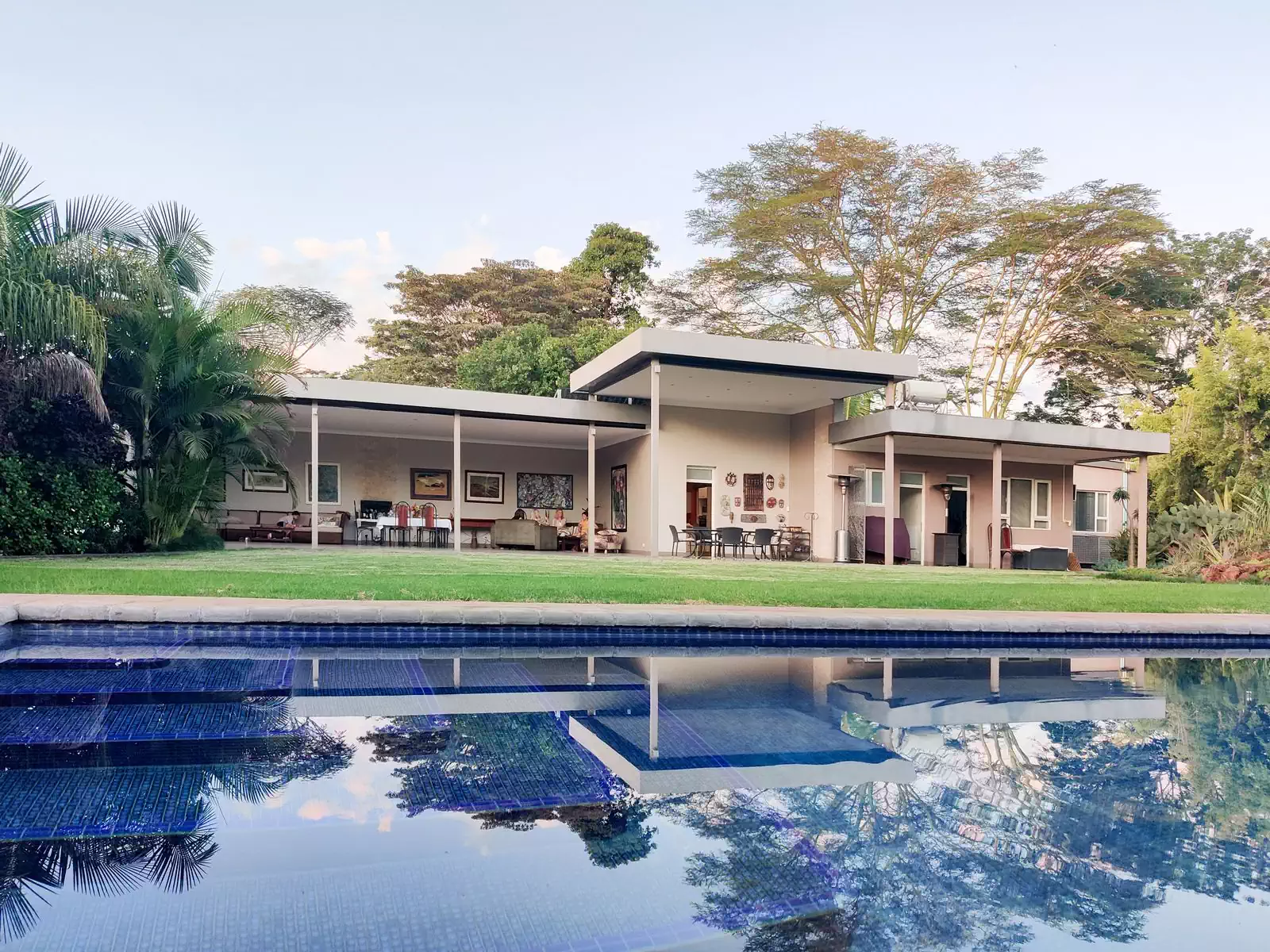 Pool overlooking modern Harare house with horizontal overhanging roof supported by steel columns. Design by architect from Harare
