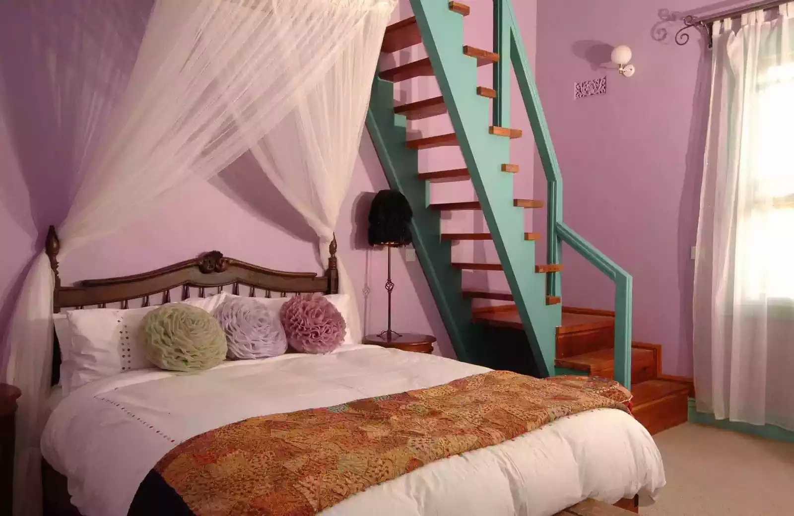 Fun purple painted bedroom with turqoise staircase in tuscan house by local architect