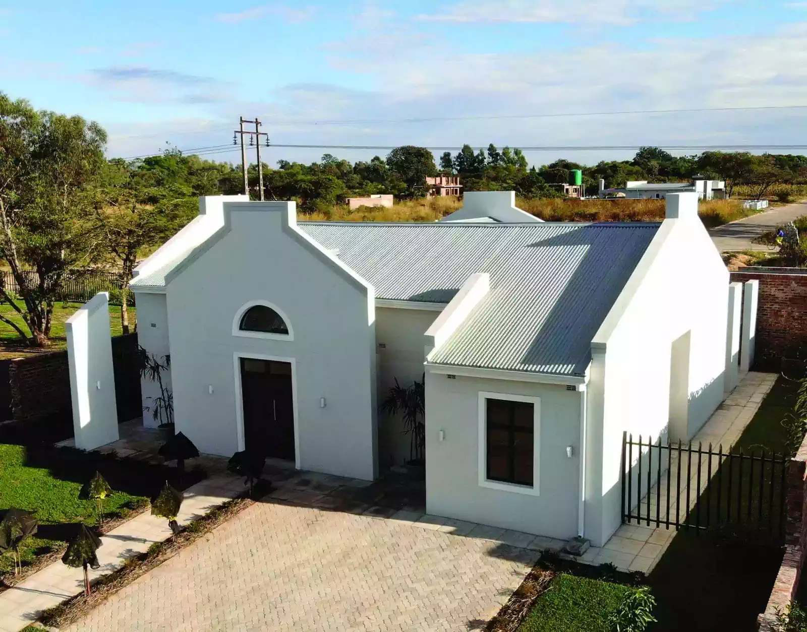 Cape dutch styled house including window surrounds and gables on all four sides. White and grey walls
