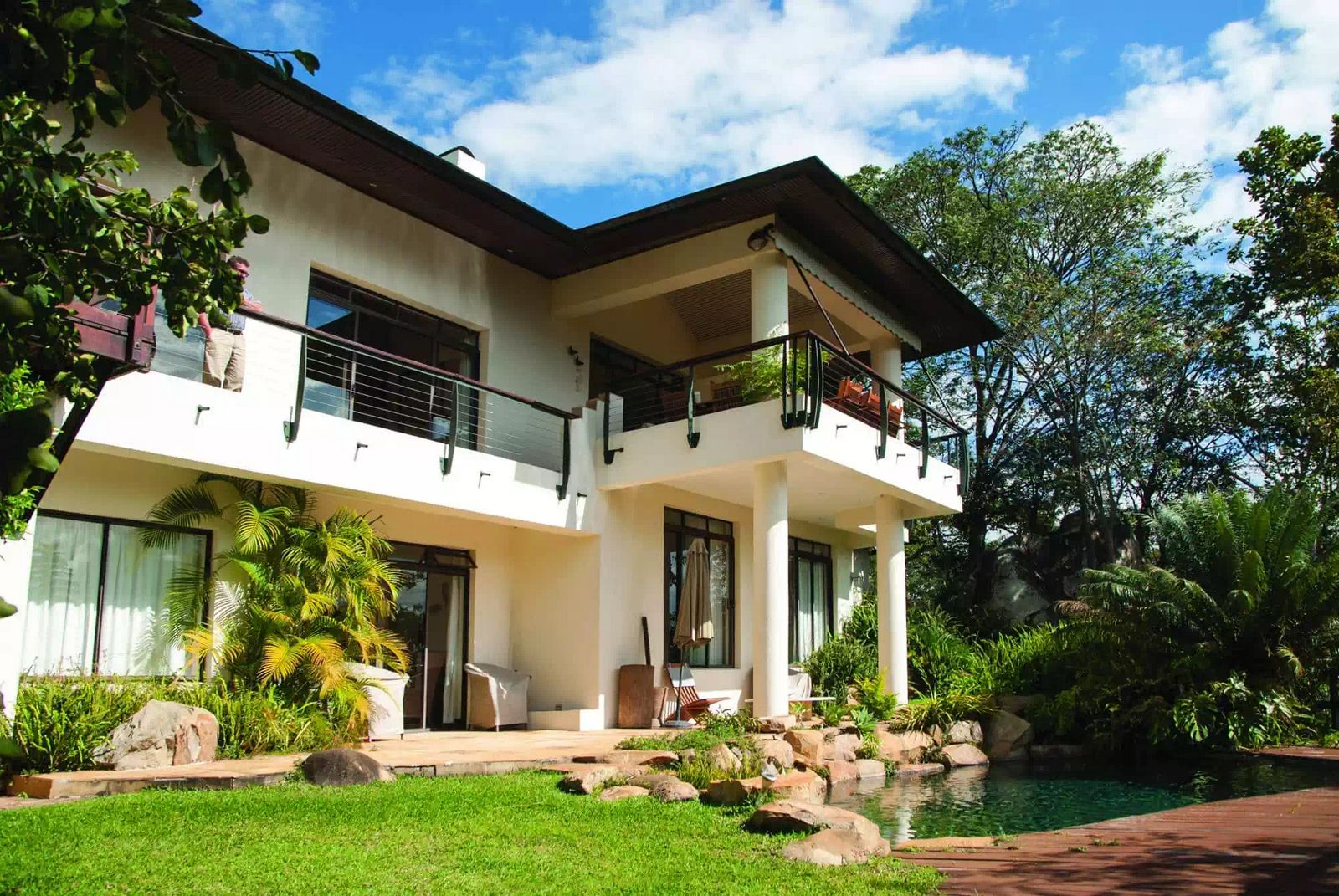 Overhanging balcony with large overhanging roof immersed in vegetation overlooking natural pool in Thetford estate by Harare architect