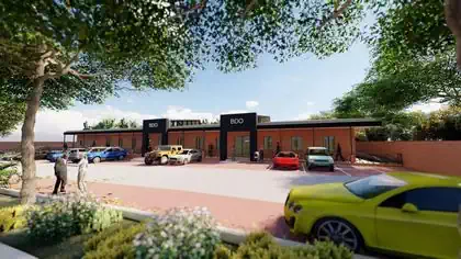 Simple modern commercial building with two pronounced entrances to shady walkway behind parking