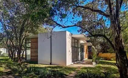 Side view of rammed earth building with large cantileavered overhangs providing shade and recessed gutter