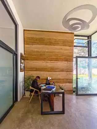 Reception area with large rammed earth wall on screed floor and glass entrance and boardroom in Zimbabwe