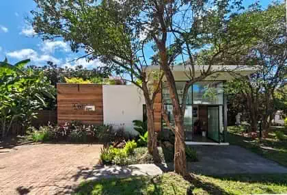 Modern glass entrance to rammed earth office building with large cantileavered overhang providing shade and green roof garden
