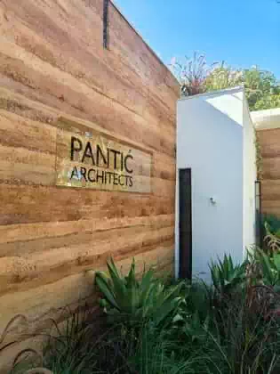 Detail of rammed earth wall and signage with green roof garden and indigenous plants in Zimbabwe