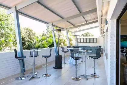 Outside fun cool covered balcony with bar stools and table in conferencing centre in Harare