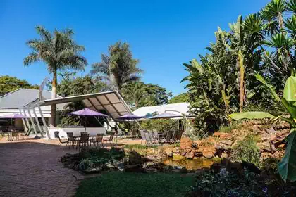 Waterfall with rocky pond in front of fun cool steel canopy over tables and reception 