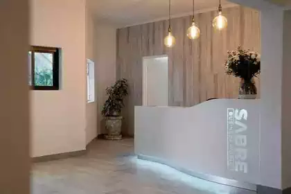Curved reception counter with pendant lights and glowing SABRE text 