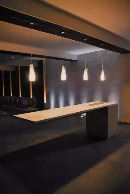 Incredible floating cantilevered tasting table with pendant lights above in wine basement
