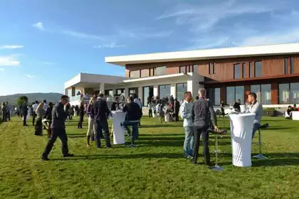 People standing in front of modern slanted cantilevered wooden Temet winery building in Serbia