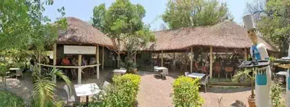 african thatched roof open restaurant building in vegetation with waiter 