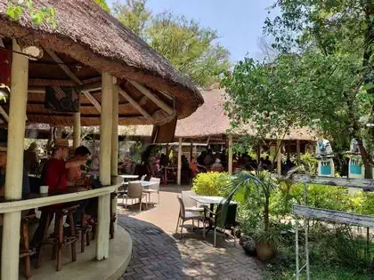 Detail of seating and thatched roof restaurant and tree covered outside seating in Victoria falls waterfall area
