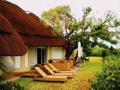 Loungers and armchairs by splash pool in front of bungalow by architect