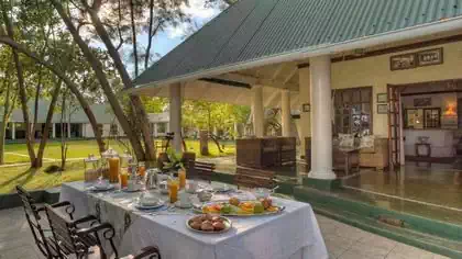 Breakfast table in front of colonial house with veranda at River Club Lodge in Livingstone Zambia