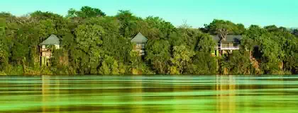 Lodge buildings and bungalows on stilts within dense vegetation overlooking Zambezi river designed by Pantic Architects