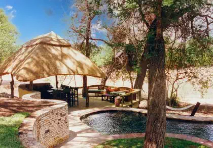 Outside gazeebo wooden gumpole structure and thatched roof