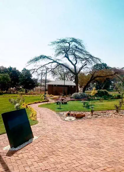 Plaque and landscaping details vegetation and pebbles with building in background in NSSA Chipinge park