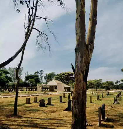 Trees and tombstones on lawn with chapel in background in graveyard