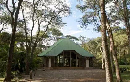 Graceful chapel entrance with large overhanging roof immersed in vegetation in Thetford estate in Harare