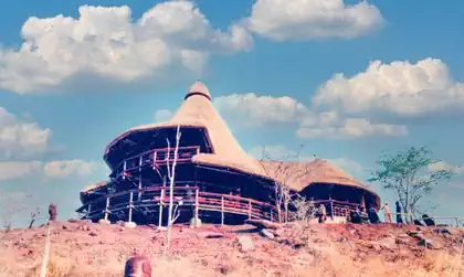 Thatched bungalow amongst trees on top of hill