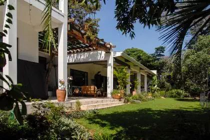 Cape Dutch style house in Harare Zimbabwe. Large shady veranda in front of living and dining room. House within trees