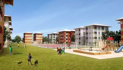 Children playing on field by playgrounds with apartment buildings behind