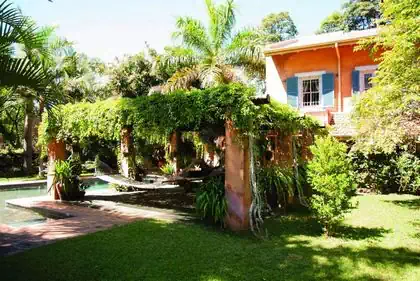 Dense shaded outside sitting and lounging area by pool in tuscan house in Harare