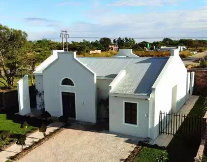 Cape dutch styled house including window surrounds and gables on all four sides. White and grey walls