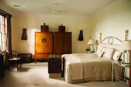 African style bedroom with trunks, sash windows and wooden cupboards in Colonial style mansion