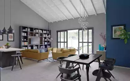 Spectacular double volume open plan living area in cape dutch styled house. Monochromatic decorations with yellow furniture. White rafters and tongue and groove wooden cladding