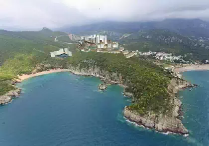 Aerial view of Penisula above Queen's beach with hotel complex and tourist resorton summit